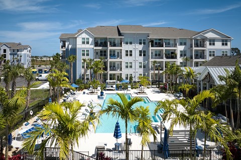 a large pool with palm trees in front of an apartment building